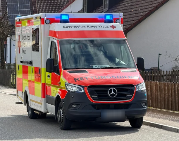 Rettungswagen des Bayerischen Roten Kreuzes in einer Wohnstraße mit Einfamilienhäusern