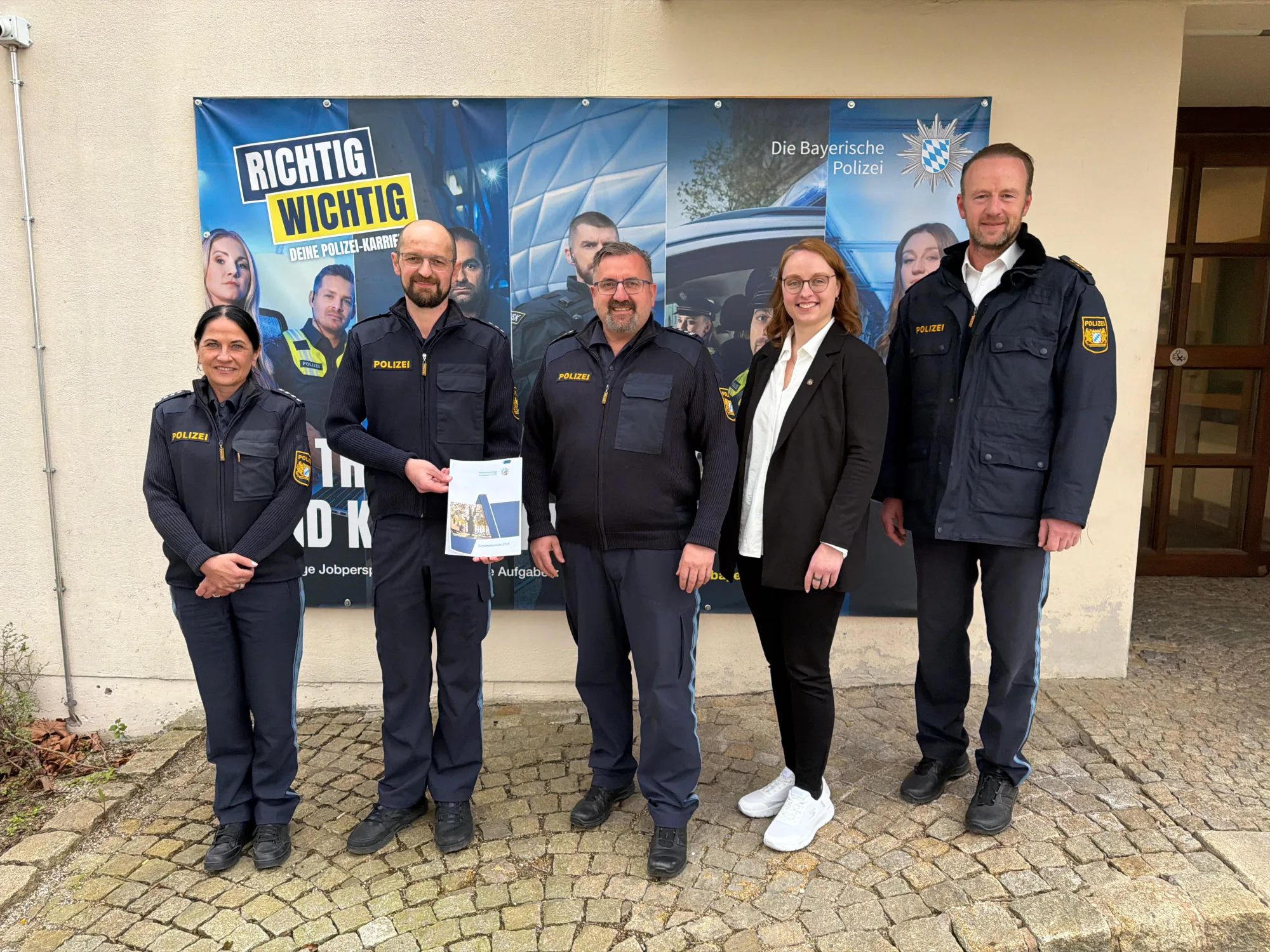 Polizeibeamte stehen vor einem Werbebanner mit der Aufschrift "richtig wichtig"