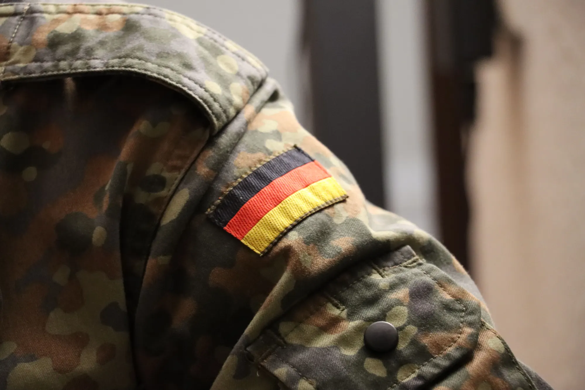Nahaufnahme einer Bundeswehr-Uniform mit Deutschland-Flagge am Ärmel in Flecktarn-Camouflage