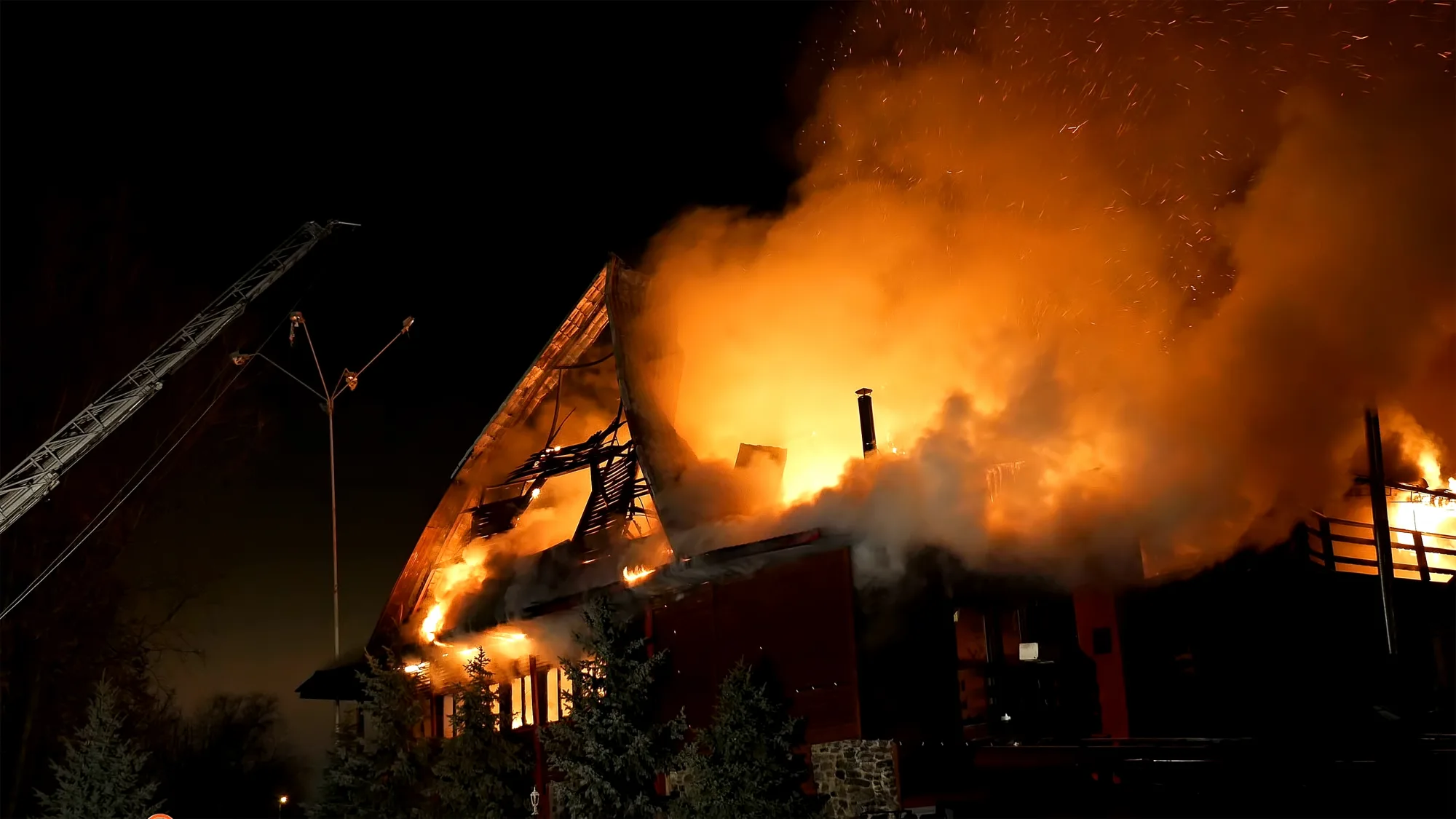 Großbrand zerstört Wohnhaus in der Nacht, Feuerwehr mit Drehleiter im Einsatz, orange Flammen und Rauch