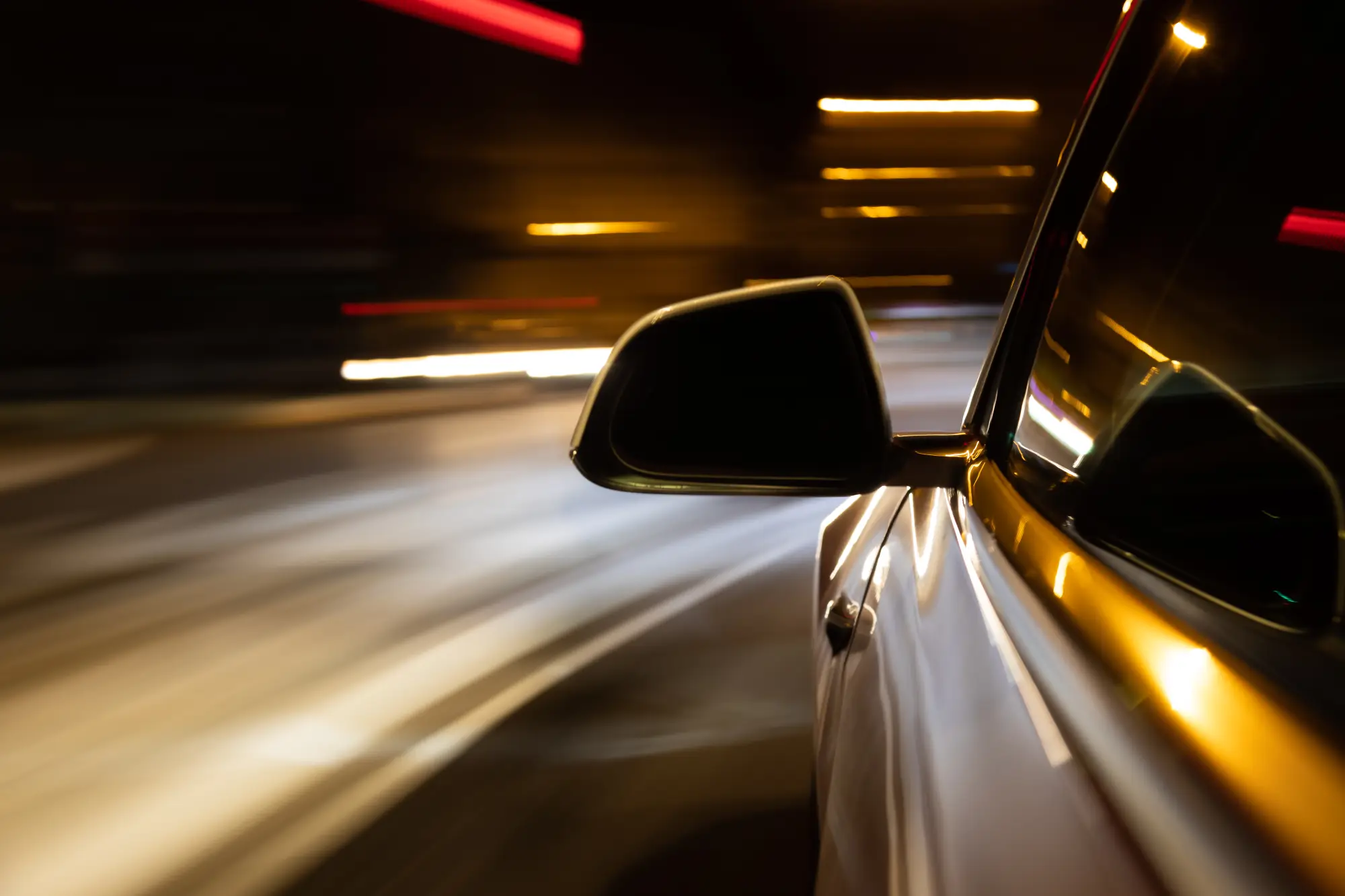 Seitliche Ansicht eines fahrenden Autos bei Nacht mit Bewegungsunschärfe und Lichtspuren im Hintergrund