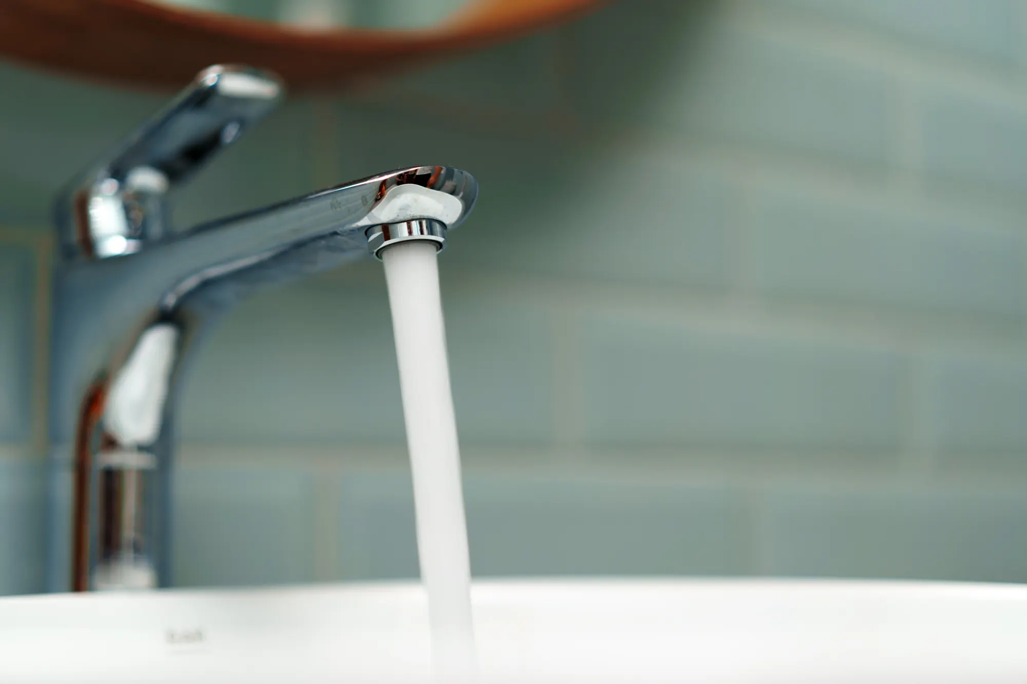 Wasserhahn mit fließendem Wasser in einem weißen Waschbecken, Nahaufnahme des Wasserstrahls
