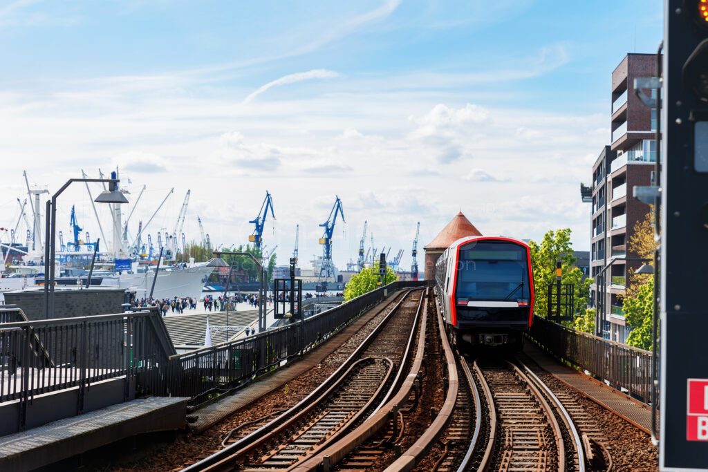 ADAC untersucht Pünktlichkeit bei S- und U-Bahnen – Hamburger U-Bahn, Haltestelle Baumwall auf Hochgleis mit Hamburger Hafenkränen und Schiffen im Hintergrund